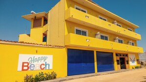 A multi-story yellow building with a sign reading 'Happy Beach.' - PLAYA FELIZ (Zihuatanejo)