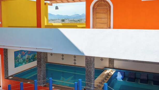 A multi-story building with a pool, balconies, and a view of the mountains. - PLAYA FELIZ (Zihuatanejo)