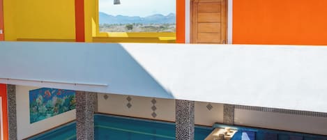 A multi-story building with a pool, balconies, and a view of the mountains.