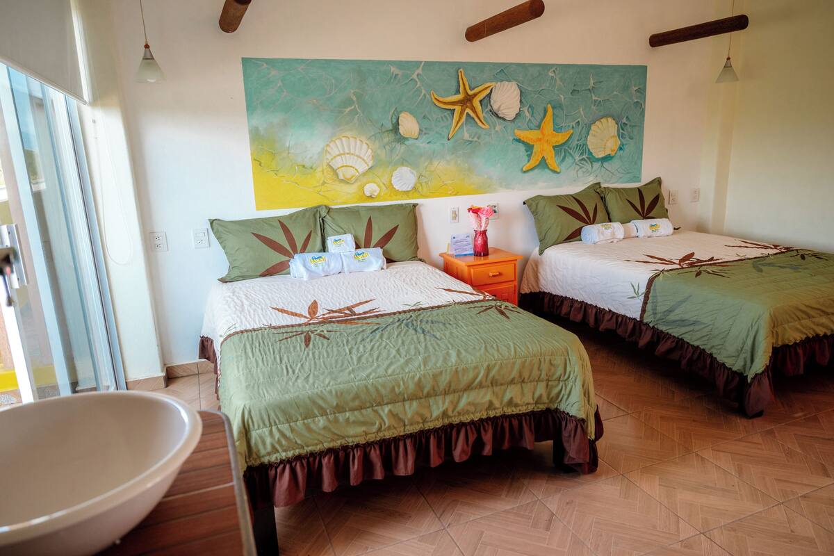 Een kamer met twee bedden, een badkamer en een wanddecoratie.