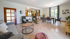 Un salon spacieux comprenant un canapé, des fauteuils, une table basse et un coin repas avec des chaises et une table.