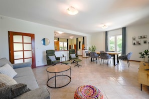 Ein geräumiges Wohnzimmer mit einer Couch, Sesseln, einem Couchtisch und einem Essbereich mit Stühlen und einem Tisch.