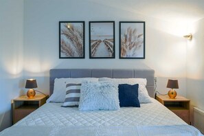 Ein Schlafzimmer mit einem Bett, zwei Nachttischen und drei gerahmten Bildern an der Wand.