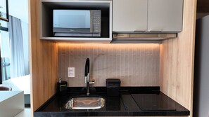 Uma cozinha moderna com micro-ondas embutido, uma pia e um armário sobre a bancada.