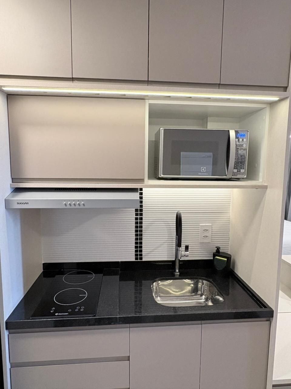 Una cocina compacta con microondas, estufa y pileta.