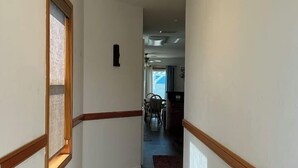 A hallway with wooden trim, a hanging light fixture, and a view into a dining area. - Beachside Vacation Home 117 #B (South Padre Island)