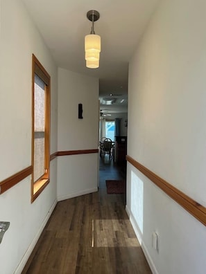 A hallway with wooden trim, a hanging light fixture, and a view into a dining area. - Beachside Vacation Home 117 #B (South Padre Island)