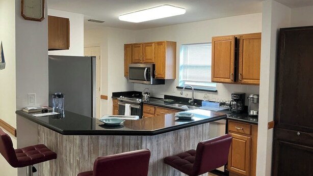A kitchen with a central island, wooden cabinets, a microwave, and a refrigerator. - Beachside Vacation Home 117 #B (South Padre Island)