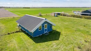 A blue house with a sloped roof and solar panels, surrounded by green fields and a clear sky. - 4 Star Holiday Home in Grevinge (Grevinge)