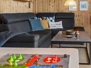 En moderne stue med en sofa, puder, et sofabord og et brætspil.