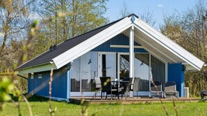 A blue house with a white roof, a covered porch with chairs, and a grassy yard. - 4 Star Holiday Home in Grevinge (Grevinge)