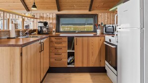A compact kitchen with wooden cabinetry, a built-in oven, a microwave, and a coffee maker. - 4 Star Holiday Home in Grevinge (Grevinge)
