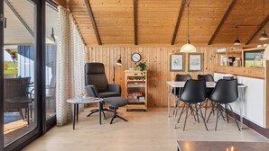 A wooden interior with a dining area, a chair, a table, and a bookshelf. - 4 Star Holiday Home in Grevinge (Grevinge)