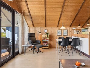 Et træinteriør med spiseplads, en stol, et bord og en reol.