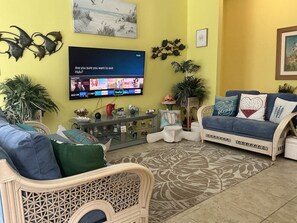Ein Wohnzimmer mit Fernseher, zwei Sofas, einem Couchtisch und Zimmerpflanzen.