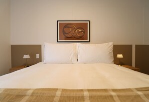 A neatly made bed with a plaid blanket, two bedside lamps, and a framed abstract artwork on the wall. - w* | Upscale 2BR with Balcony in Miraflores (Miraflores)