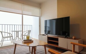 A modern living room with a large flat-screen TV, a wooden coffee table, a sofa, and a balcony with a railing. - w* | Upscale 2BR with Balcony in Miraflores (Miraflores)
