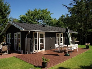 Ein kleines Haus mit Terrasse, einem Patio-Tisch und Stühlen.