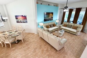 Un salon comprenant un ensemble de canapés, une table à manger avec des chaises et deux tableaux accrochés au mur.