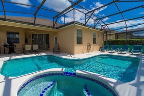 Une piscine avec un jacuzzi, des chaises longues et un espace patio couvert.