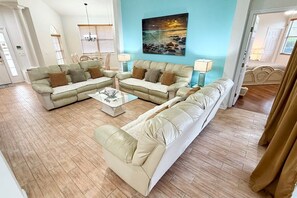 Un salon avec un canapé d’angle, une table basse et un tableau accroché au mur.