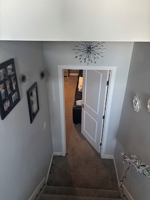 A hallway with a door leading to a room, a framed picture on the wall, and a decorative light fixture.