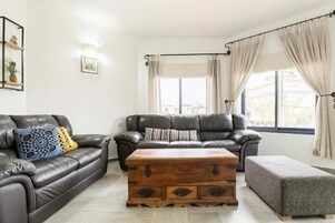 A living room with two leather sofas, a wooden coffee table, and a grey ottoman.
