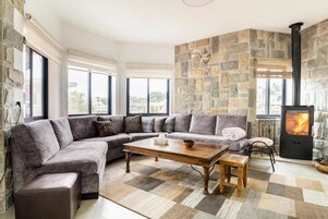 A modern living room with a stone wall, a large sectional sofa, a wooden coffee table, and a fireplace.