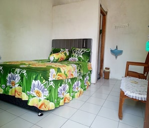 A room with a bed, a chair, a sink, and a door.