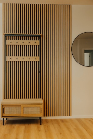 Une pièce avec un mur composé de lattes de bois, un miroir rond et un banc en bois doté de portes en osier tressé.
