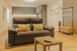 Un salon moderne avec un canapé, une table basse et un coin cuisine à l’arrière-plan.