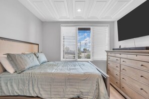 A bedroom with a bed, dresser, and a TV mounted on the wall.