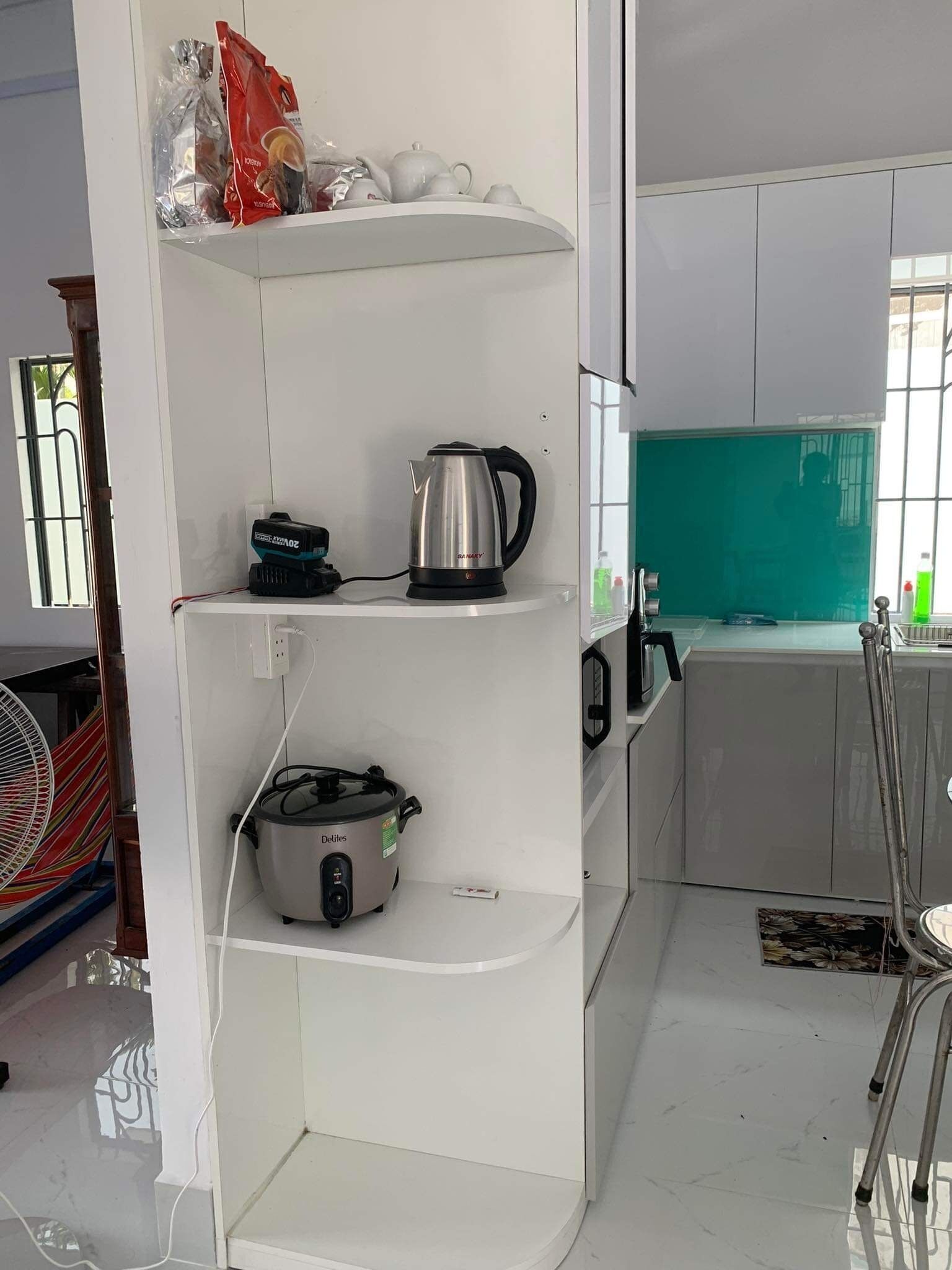 A kitchen with white cabinets, a kettle, a rice cooker, and a fan.