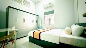 A bedroom with a bed, a desk, a wardrobe, and an air conditioning unit. - 3-bedroom house in welcoming Thanh Dien with AC comfort (Thanh Dien)