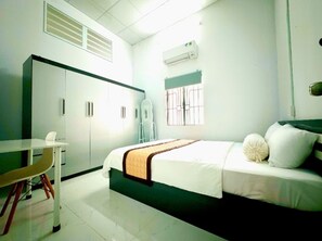 A bedroom with a bed, a desk, a wardrobe, and an air conditioning unit. - 3-bedroom house in welcoming Thanh Dien with AC comfort (Thanh Dien)
