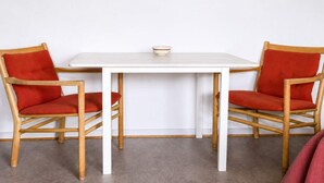 A white table with two red chairs, a white bowl on the table, and a white spherical object on the wall. - 4 Star Holiday Home in Grenaa (Grenaa)