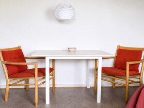 A white table with two red chairs, a white bowl on the table, and a white spherical object on the wall. - 4 Star Holiday Home in Grenaa (Grenaa)