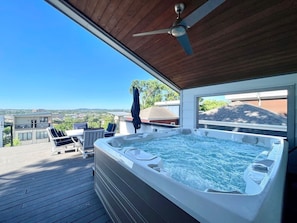 A hot tub on a wooden deck with a clear view of the surrounding area.
