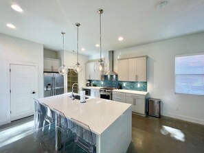 A modern kitchen with a central island, stainless steel appliances, and pendant lighting.