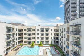 A multi-story residential building with a central courtyard featuring a swimming pool, outdoor seating, and greenery. - Urban Houston Stay 1BR • Balcony • Fast Wi-Fi  Laundry (Houston)