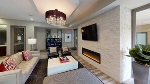A modern living room with a fireplace, a flat-screen TV, and a chandelier. - Urban Houston Stay 1BR • Balcony • Fast Wi-Fi  Laundry (Houston)