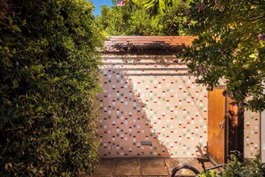 Un jardín con un muro decorativo, una puerta de madera y una bicicleta.