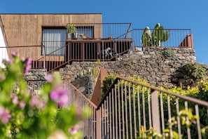 A modern building with a wooden facade, stone steps, and a metal railing.