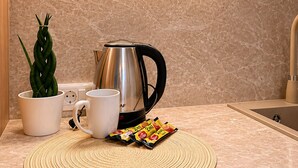 A kitchen with a coffee maker, a mug, a plant, and a woven placemat on the counter. - Villa Lucija - Old town and Lake view Apartment (Ohër)