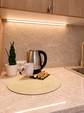 Una cucina con una macchina da caffè, una tazza, una pianta e un sottopentola intrecciato sul bancone.