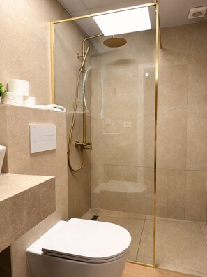 Un baño moderno con ducha de vidrio, inodoro y lavamanos.