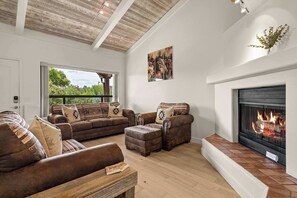 Ein Wohnzimmer mit Kamin, Ledersofas und einem großen Fenster.