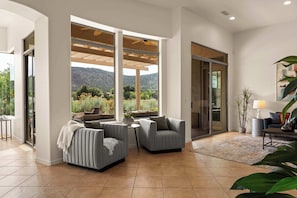 Ein modernes Wohnzimmer mit großem Fenster, Deckenventilator und Blick auf eine Berglandschaft.
