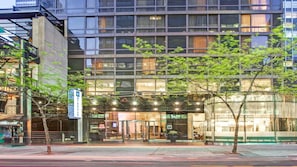 Um hotel moderno com fachada de vidro, entrada visível e uma placa indicando a marca Wyndham.