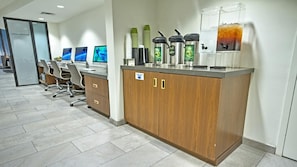 A modern office with a reception desk, computer monitors, and a coffee station.